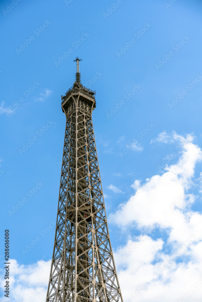 Truss top part of Eiffel Tower on the background of the cloudy sky Truss top part of Eiffel Tower on the background of the cloudy sky