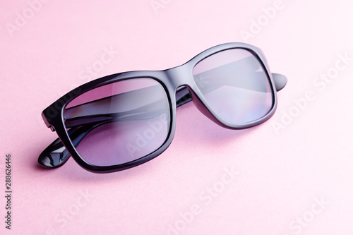 Fashionable purple color sunglasses closeup on pink background