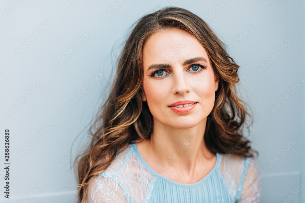 Outdoor portrait of beautiful woman with curly hair, wearing blue dress Outdoor portrait of beautiful woman with curly hair, wearing blue dress