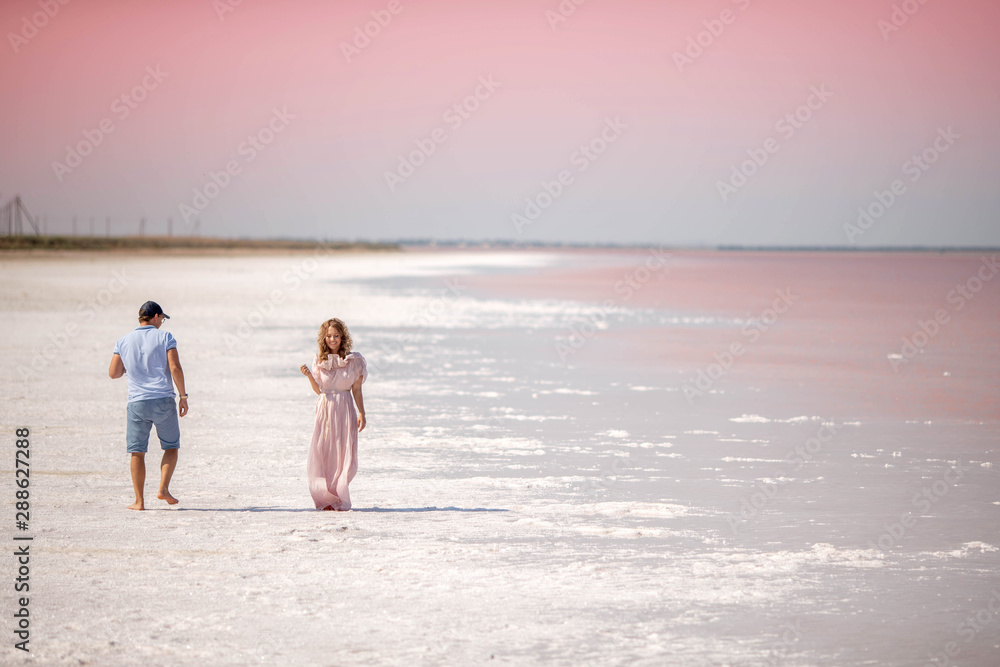 A guy looks at a girl on a pink lake.