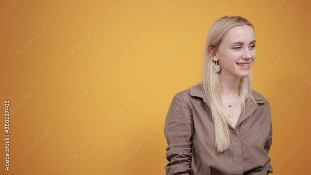 blonde girl in brown blouse over isolated orange background shows emotions blonde girl in brown blouse over isolated orange background shows emotions