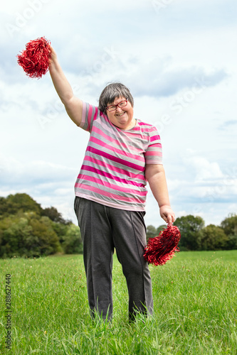 Geistig behinderte Frau tanzt mit Pom Poms auf der Wiese, Freizeitgestaltung photo