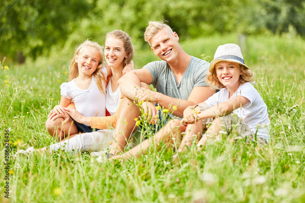Fototapeta premium Glückliche Familie sitzt entspannt im Gras
