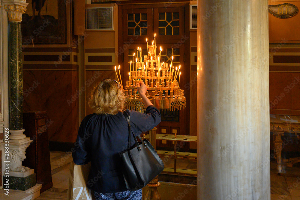 Frau zündet in einer orthodoxen Kirche eine Kerze an, Athen, Griechenland