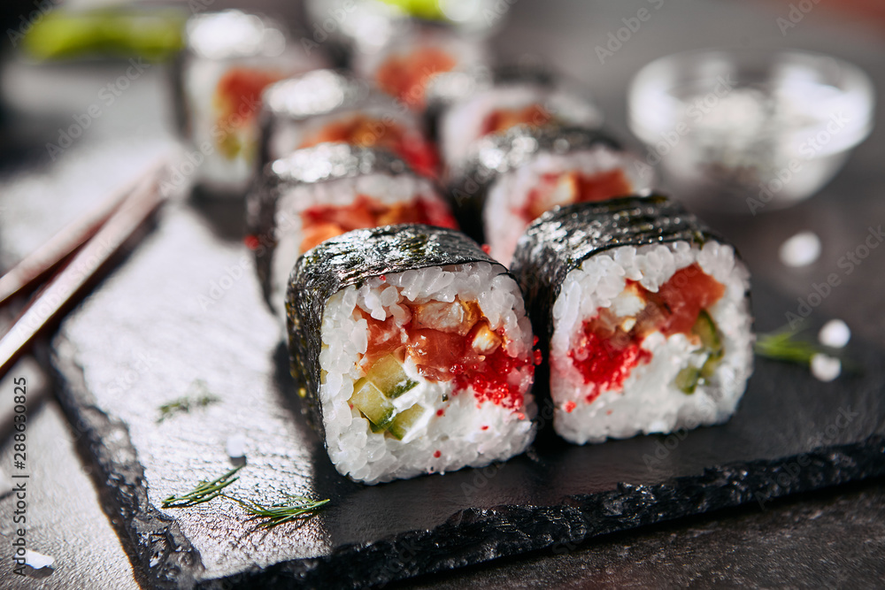 Macro photo of dragon roll with cream cheese, salmon, eel, rice, cucumber, flying fish caviar and nori. Dragon unagi maki rolls with raw red fish and tobiko on natural dark stone background close up Macro photo of dragon roll with cream cheese, salmon, eel, rice, cucumber, flying fish caviar and nori. Dragon unagi maki rolls with raw red fish and tobiko on natural dark stone background close up