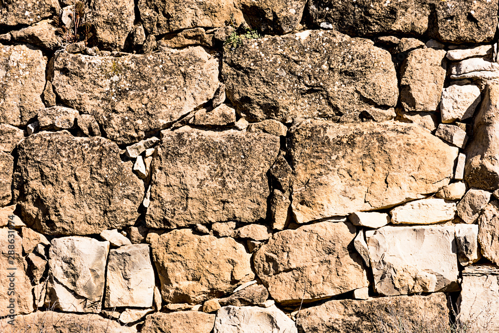 Fototapeta premium Ancient stone wall in a rural zone. Old stones texture. Dry stone