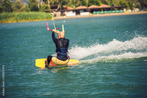Professional kiter makes the difficult trick on a beautiful background. Kitesurfing Kiteboarding action photos man among waves quickly goes