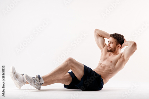 young man with a beard of a sports physique does an exercise on the muscles of the abdominal cavity on a white isolated background, the athlete goes in for sports, exercise on the muscles of the press