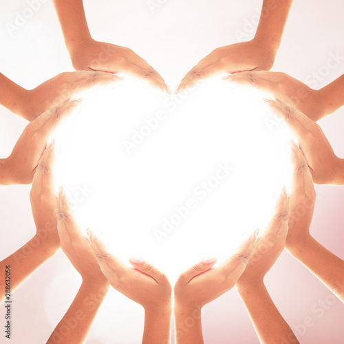 International human solidarity day concept: Human hands in shape of heart on blurred natural background