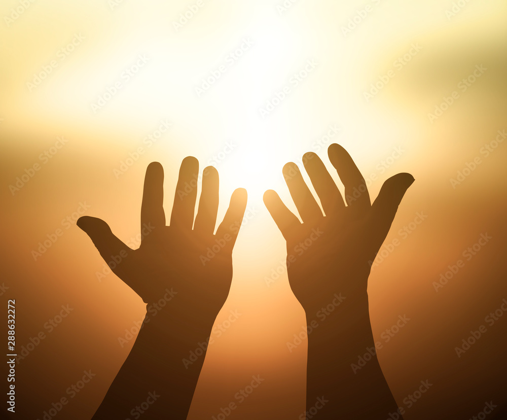 Ascension day concept: Silhouette hands of God over blurred autumn sunset background