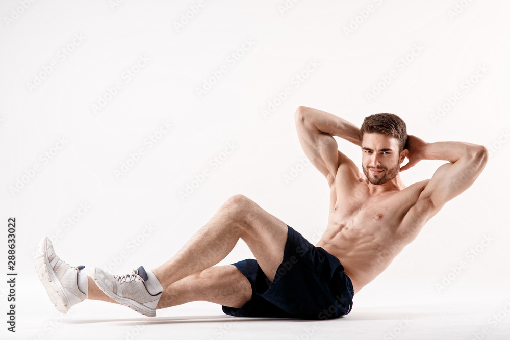Obraz premium young man with a beard of a sports physique does an exercise on the muscles of the abdominal cavity on a white isolated background, the athlete goes in for sports, exercise on the muscles of the press