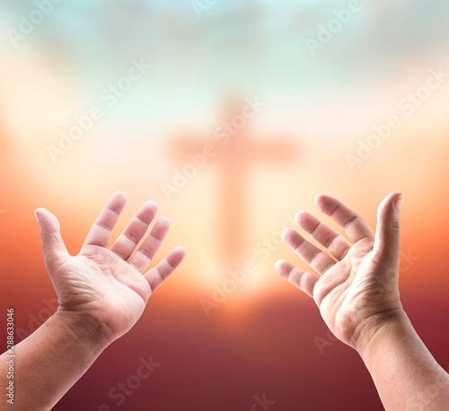 Worship God concept: Silhouette christian hands over blurred cross sunset background photo