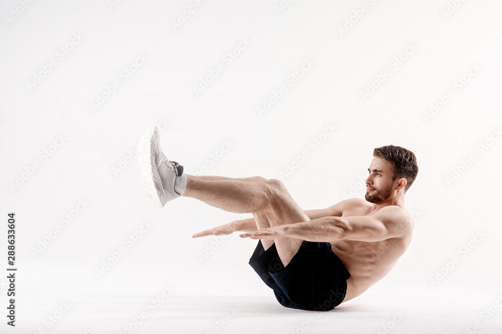 © Ilnur - young man with a beard of a sports physique does an exercise on the muscles of the abdominal cavity on a white isolated background, the athlete goes in for sports, exercise on the muscles of the press