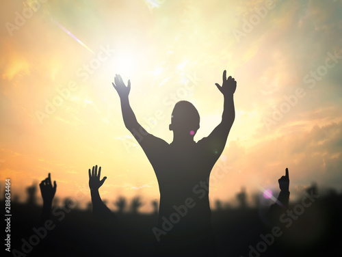 Worship concept: Silhouette of a man with raised hands over blurred nature background photo