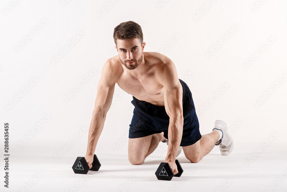 A man on a white isolated background is pushing up on the floor with dumbbells. Bearded bodybuilder athletic A man on a white isolated background is pushing up on the floor with dumbbells. Bearded bodybuilder athletic