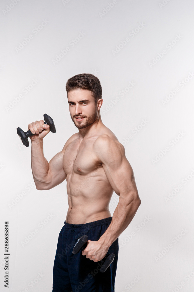 Young athlete on a white background lifts dumbbells. training a bearded man athletic build