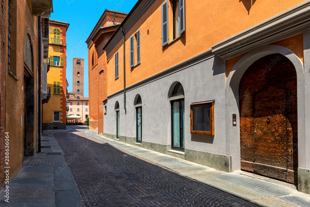 Narrow,cobblestone street among old colorful houses in Alba, Italy.