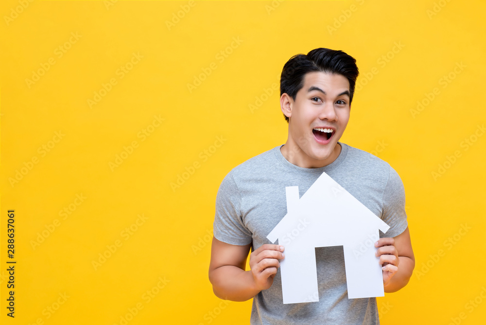 Portrait of young handsome happy Asian man holding paper home Portrait of young handsome happy Asian man holding paper home