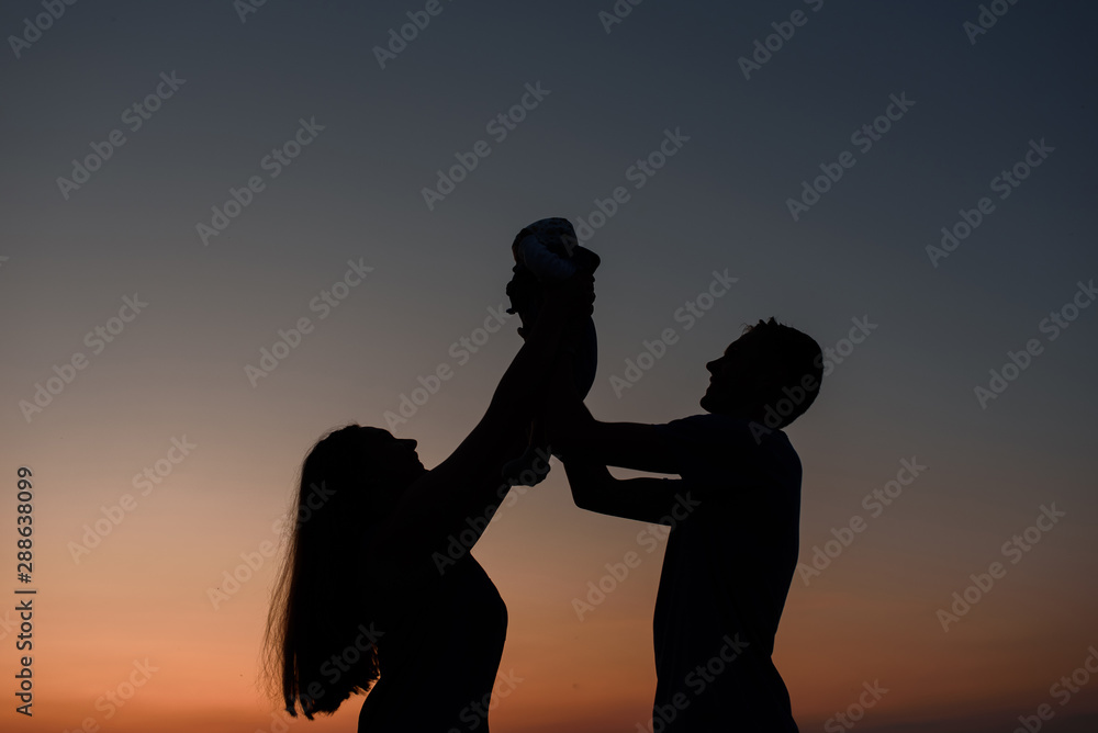 Young parents walk with their little son in the field