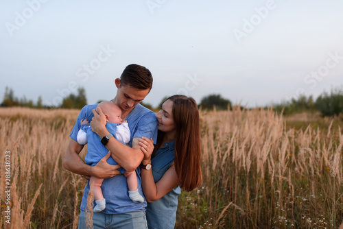Young parents walk with their little son in the field
