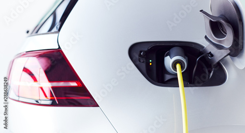 Close Up Of Power Cable Charging Environmentally Friendly Zero Emission Electric Car In Garage photo