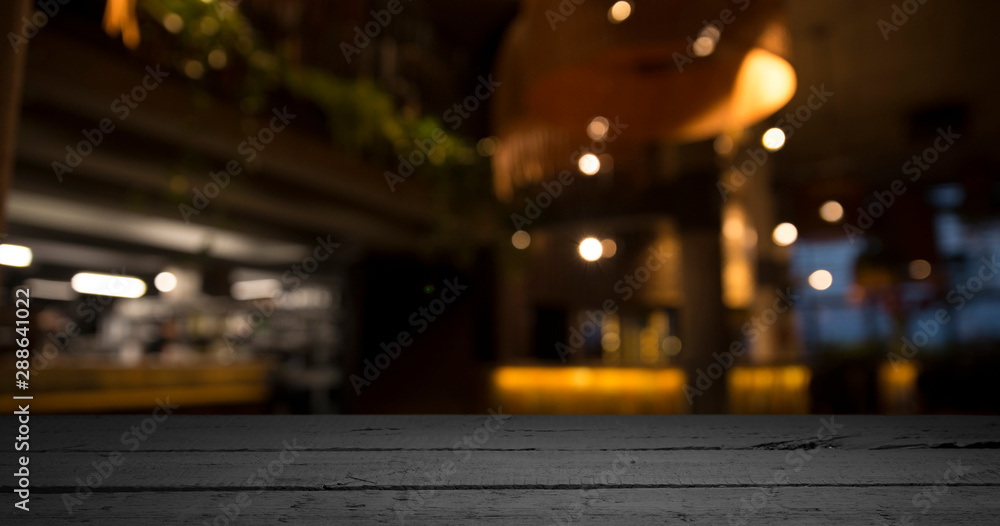 Empty wood table top on blur light gold bokeh of cafe restaurant in dark background