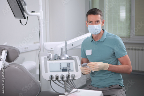 Dentist doctor man in the office. Face in the mask. The concept of prophylactic and dental treatment.