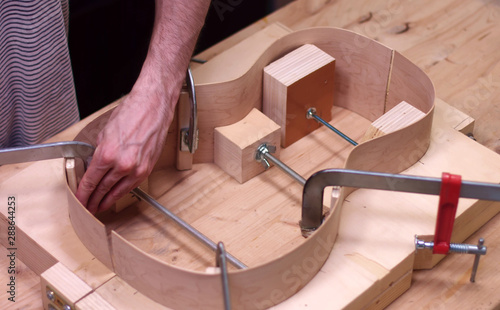 Luthier constructs an acoustic guitar in his shop