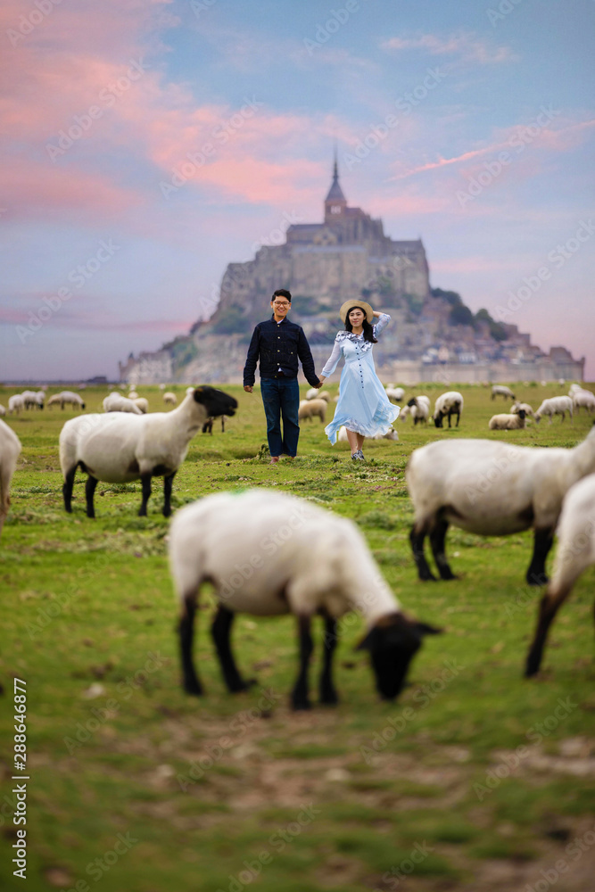 Fototapeta premium Young couple is travel at Mont Saint Michel during summer time in Normandy,France as for pre-wedding photograph.