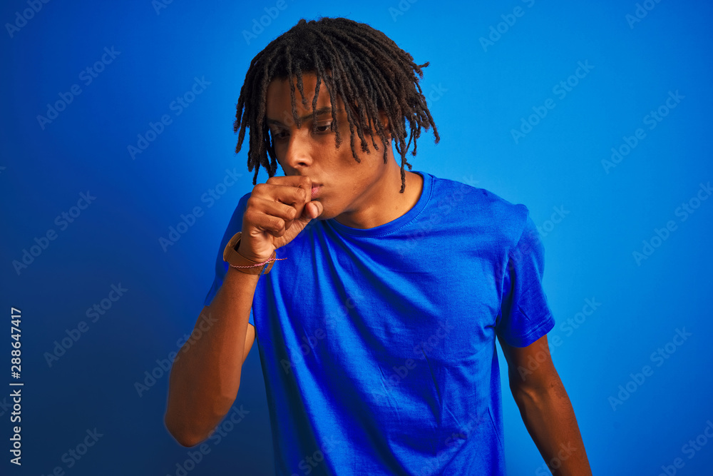 Afro american man with dreadlocks wearing t-shirt standing over isolated blue background feeling unwell and coughing as symptom for cold or bronchitis. Healthcare concept. Afro american man with dreadlocks wearing t-shirt standing over isolated blue background feeling unwell and coughing as symptom for cold or bronchitis. Healthcare concept.