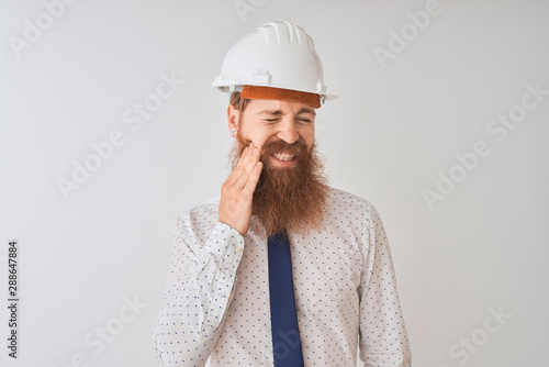 Young redhead irish architect man wearing security helmet over isolated white background touching mouth with hand with painful expression because of toothache or dental illness on teeth.