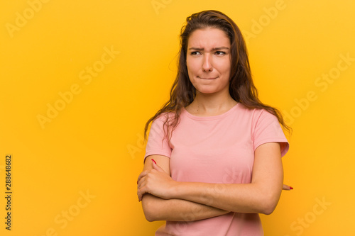 Young european woman isolated over yellow background confused, feels doubtful and unsure.