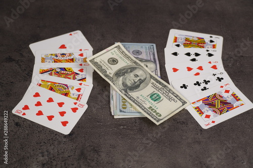 The combination of Flash Royal cards on a gray table with money and gold. Close-up. Poker game
