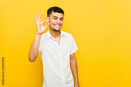 Young hispanic man cheerful and confident showing ok gesture.