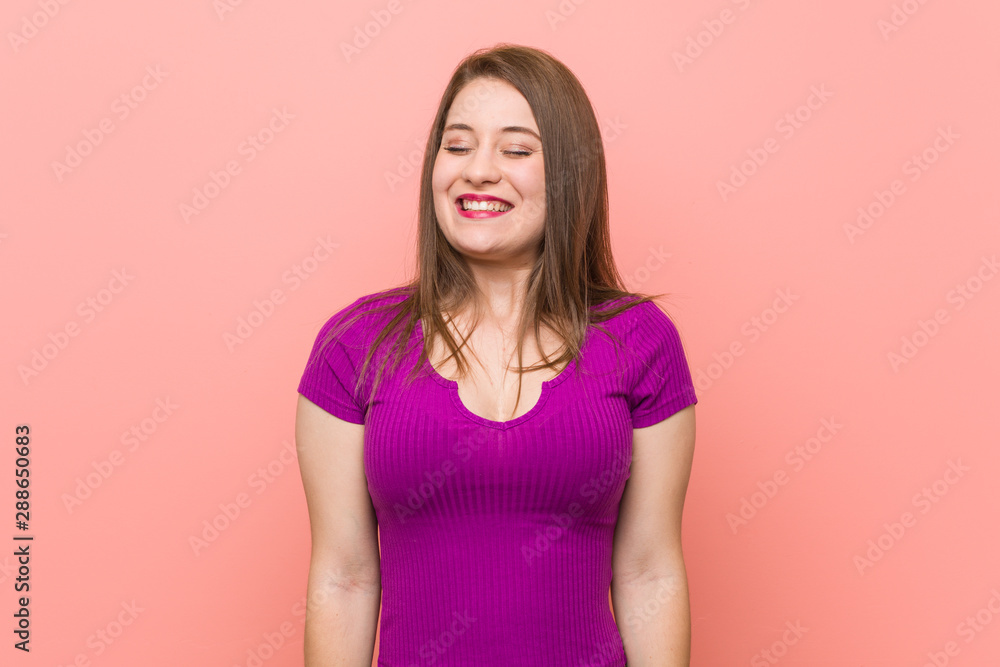 Young hispanic woman against a pink wall laughs and closes eyes, feels relaxed and happy. Young hispanic woman against a pink wall laughs and closes eyes, feels relaxed and happy.