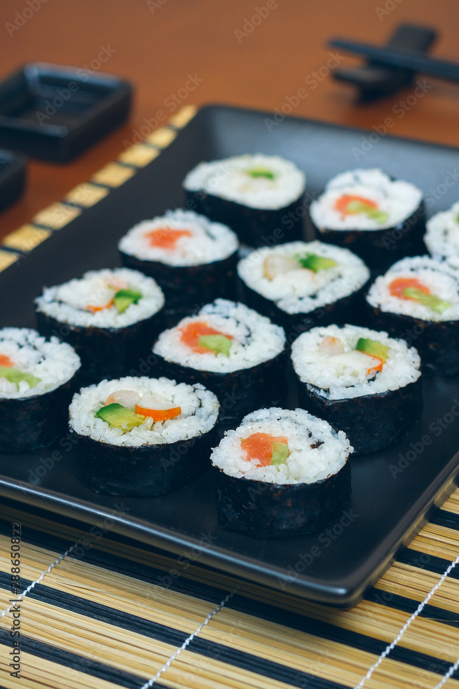Sushi maki rolls presented on a tray with sauces and chopsticks Sushi maki rolls presented on a tray with sauces and chopsticks