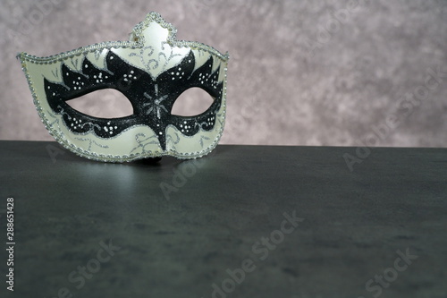 Photo of elegant white and black venetian, carnaval mask over dark background. Vintage photo