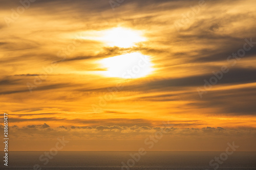 Dramatic golden rays sunset or sunrise with clouds over the ocean.