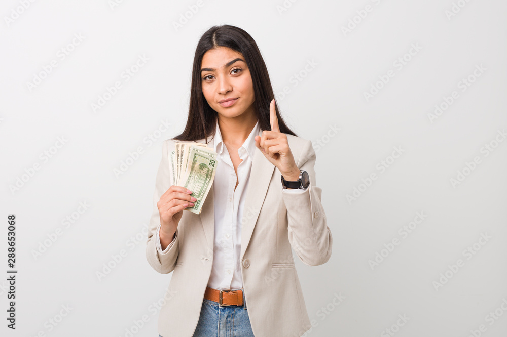 Young arab business woman holding dollars showing number one with finger. Young arab business woman holding dollars showing number one with finger.