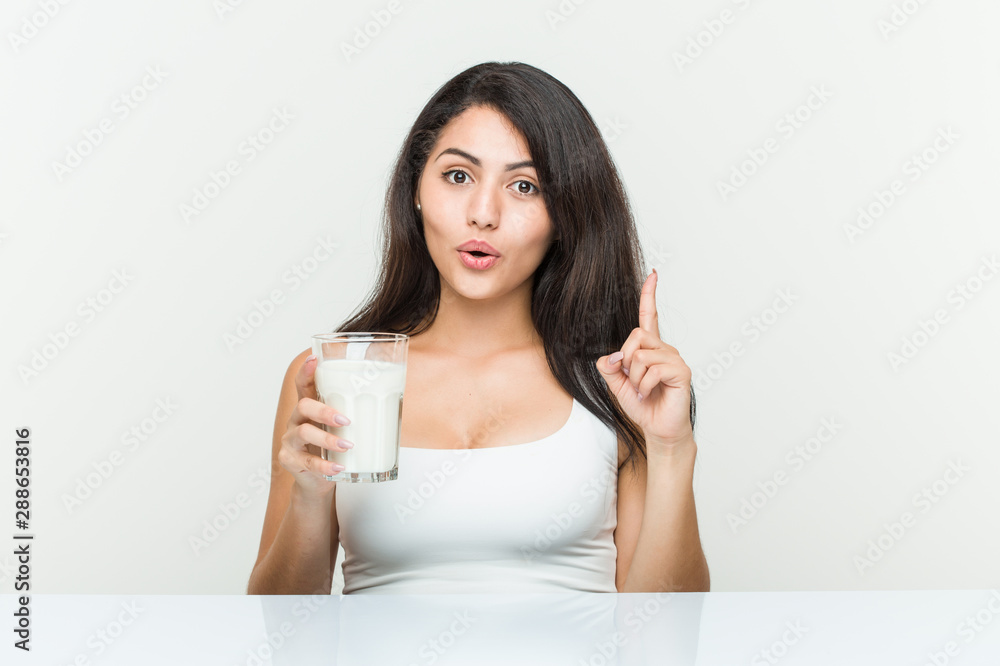 Young hispanic woman holding a glass of milk having some great idea, concept of creativity. Young hispanic woman holding a glass of milk having some great idea, concept of creativity.