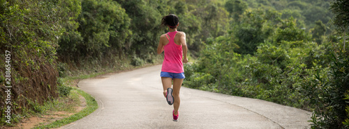 Photography Sporty young woman in sportswear trail running on forest mountain path