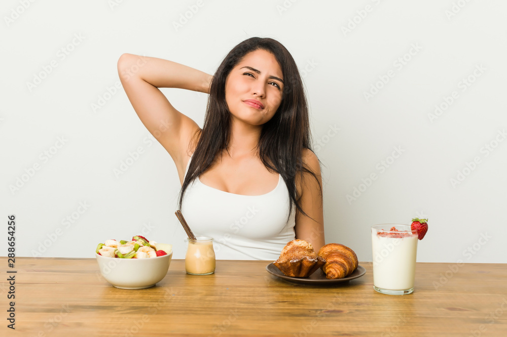 Young curvy woman taking a breakfast touching back of head, thinking and making a choice. Young curvy woman taking a breakfast touching back of head, thinking and making a choice.