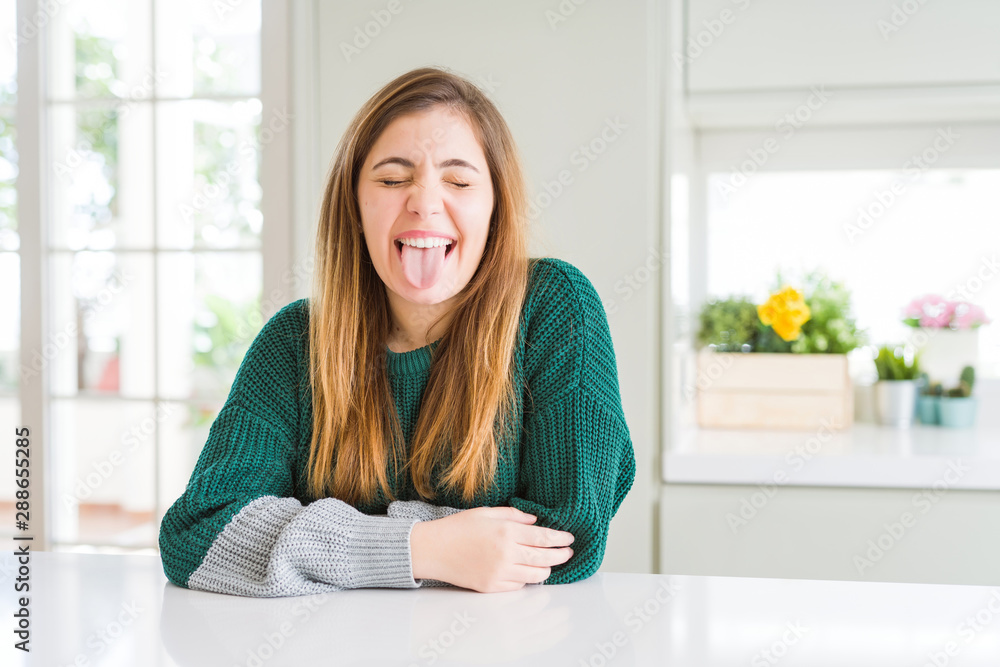 Young beautiful plus size woman wearing casual striped sweater sticking tongue out happy with funny expression. Emotion concept. Young beautiful plus size woman wearing casual striped sweater sticking tongue out happy with funny expression. Emotion concept.