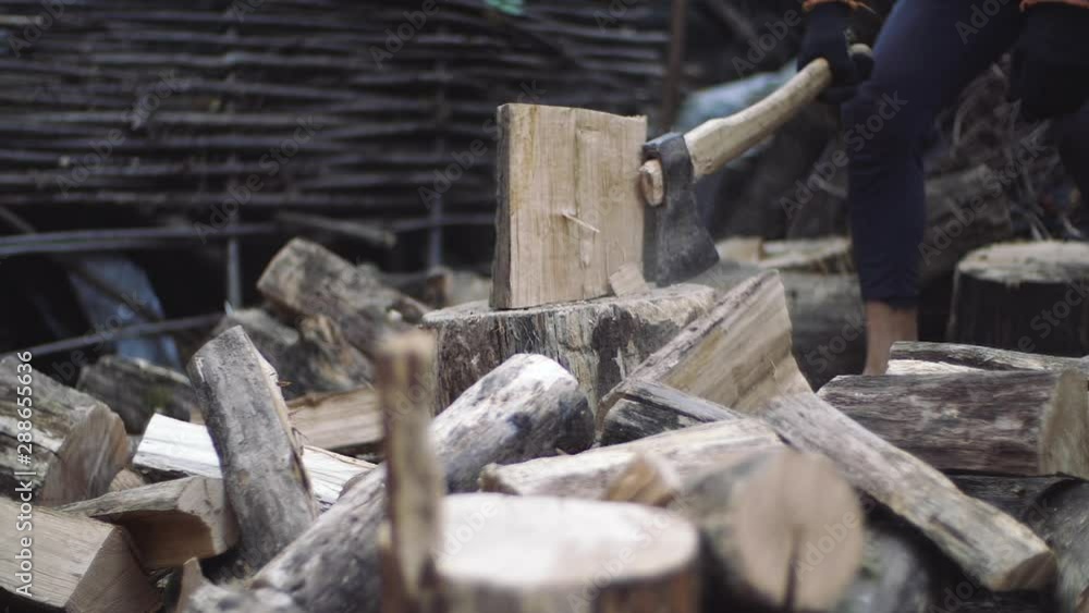 Man chops wood outdoors in slow motion. Man's hands working with ax. A man woodcutter chops tree trunks with an ax for firewood. Man chops wood outdoors in slow motion. Man's hands working with ax. A man woodcutter chops tree trunks with an ax for firewood.