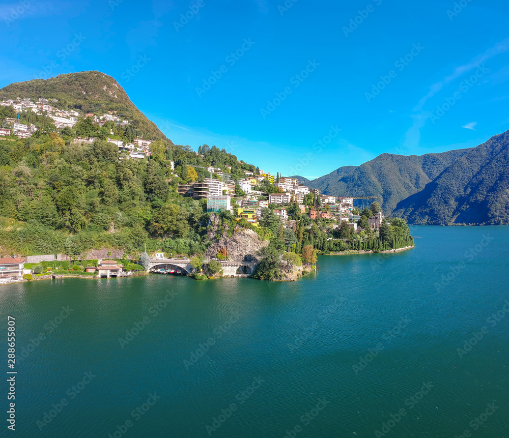 Panorama aerial view of the lake Lugano, mountains and city Lugano, Ticino canton, Switzerland. Scenic beautiful Swiss town with luxury villas. Famous tourist destination in South Europe