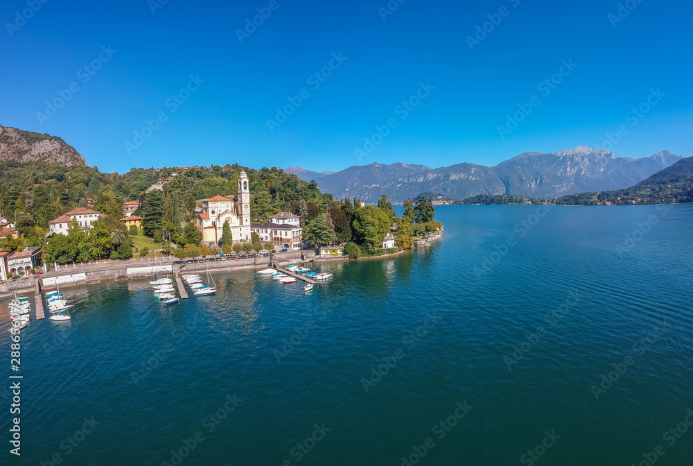 Aerial view landscape on beatiful Lake Como in Tremezzina, Lombardy, Italy. Scenic small town with traditional houses and clear blue water. Summer tourist vacation on rich resort with nice harbour