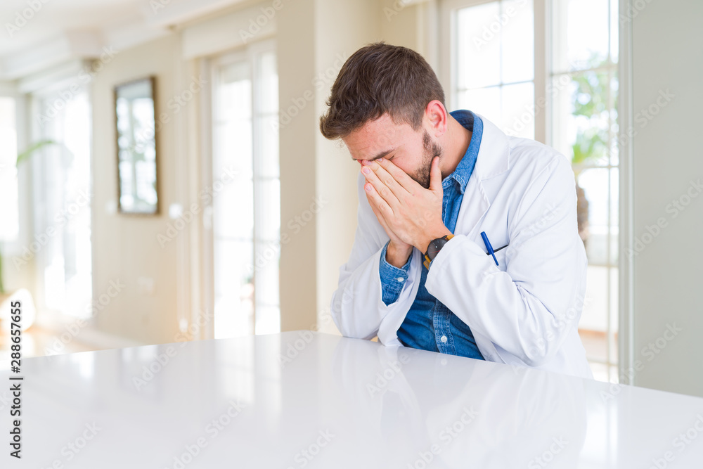 Handsome doctor man wearing medical coat at the clinic with sad expression covering face with hands while crying. Depression concept. Handsome doctor man wearing medical coat at the clinic with sad expression covering face with hands while crying. Depression concept.