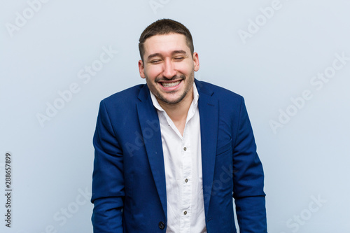 Young business caucasian man laughs and closes eyes, feels relaxed and happy.