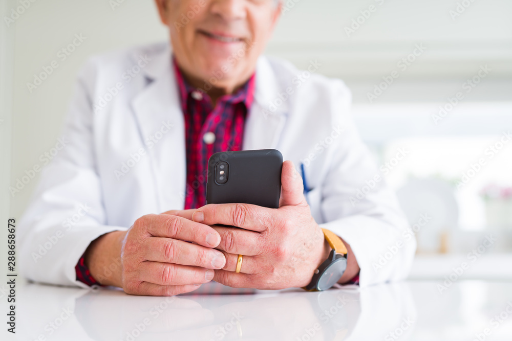 Close up of doctor hands using smartphone at the clinic and smiling Close up of doctor hands using smartphone at the clinic and smiling