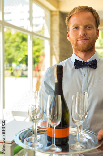 Portrait of confident young waiter serving wine at restaurant photo